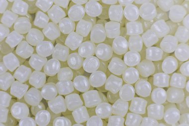 Ahşap arka planda beyaz plastik boncuklar polimer reçine, polimer palet petrokimyasal fabrikalardan alınmış ürünler. granüller polimer,