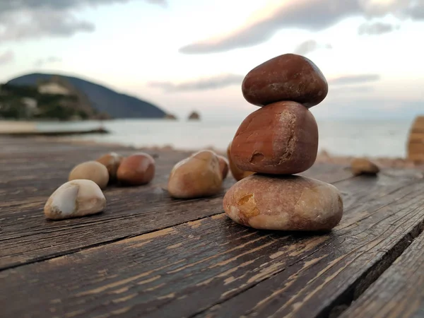 Bir deniz manzarasının arka planında, ahşap bir zemin üzerinde çakıl piramit. Dinlenme, rahatlama, sakinlik atmosferi