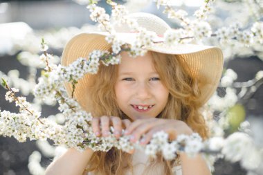  Kıvırcık sarı saçlar çiçek açan bahçede gülümseyen güzel kız.