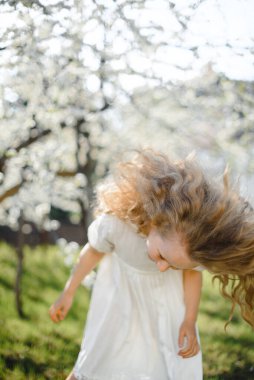  Kıvırcık sarı saçlar çiçek açan bahçede gülümseyen güzel kız.