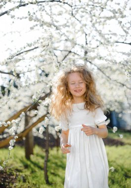  Kıvırcık sarı saçlar çiçek açan bahçede gülümseyen güzel kız.