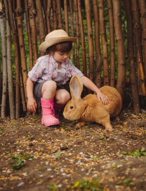 Kovboy şapkalı şirin küçük kız. Büyük tavşan, büyük kulaklı kırmızı tavşan.