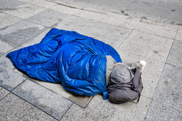 Homeless man lying on the street near Nathan Phillips square in Toronto downtown