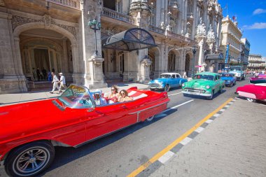 Havana, Küba 16 Aralık 2019: Mutlu turistler Paseo del Prado, El Capitolio ve Havana tarihi şehir merkezi boyunca ünlü renkli Küba taksileriyle taksi turu yapıyorlar.