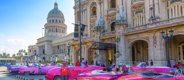 Havana, Cuba 16 December, 2019: Vintage colorful taxis waiting for tourists close to National Capitol Building (El Capitolio) on Paseo del Prado street in front of Gran Havana theater