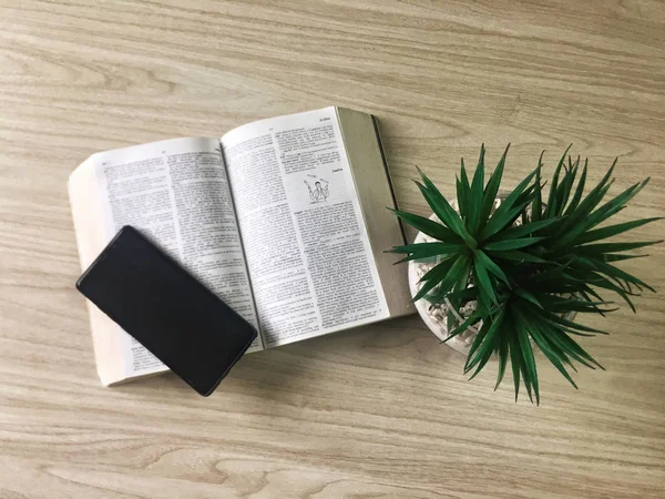 ahşap arka planda phablet, kitap ve bitki