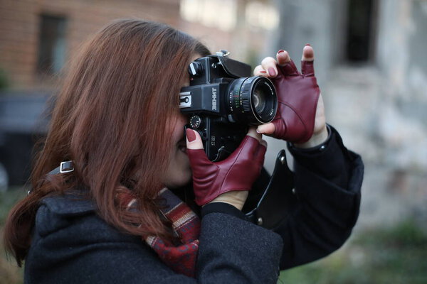 Girl with camera in gloves, girl photographer on the street