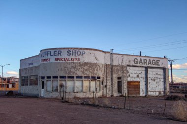 Holbrook, Arizona / USA March 9, 2019: Abandoned Muffler Shop at dusk  clipart