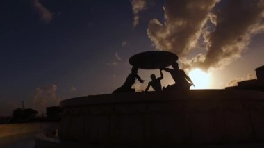 Valletta, Malta 'daki Triton Çeşmesi' nin siluetinin üzerindeki yumuşak bulutlar