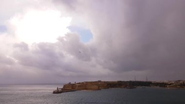 Malta üzerinde fırtınalı bulutlarda uçan uçak. Valletta Büyük Limanı