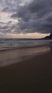 Dikey video. Ipanema Sahili, Rio de Janeiro, Brezilya. Alacakaranlıktaki Sahilde