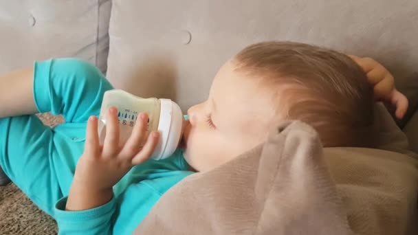 Close-up van kleine jongen kind drinken melk uit fles en kraken hoofd — Stockvideo