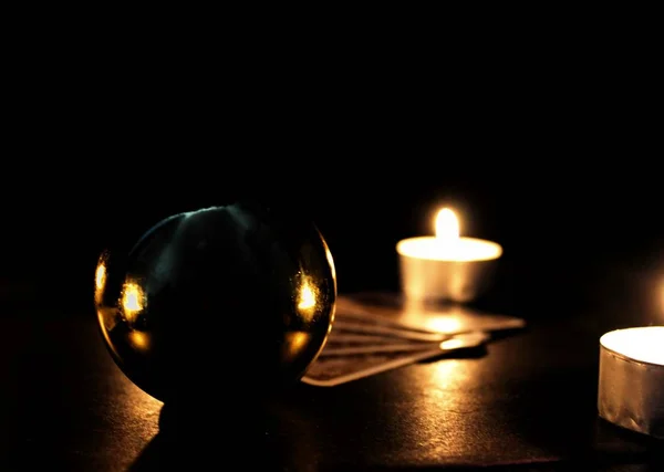Tarot cards and magic ball, candles on black background