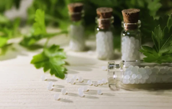 Homeopathy pills in vintage bottles on wood and green background. A bottle of homeopathic remedies