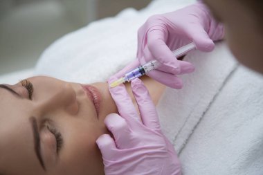 Kız kozmetoloji ofisinde dudak büyütme prosedürü yapar