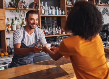 Apron mutlu bir genç erkek barista Portresi kafede tezgahta kadın müşteri ye bir kahve fincanı hizmet vermektedir