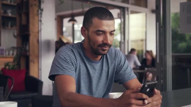 Mensajería de texto hombre joven en el teléfono móvil en la cafetería — Vídeo de stock