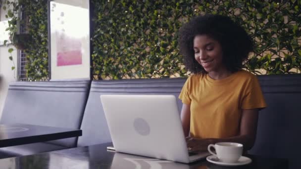 Молодая улыбающаяся женщина с ноутбуком в кафе — стоковое видео