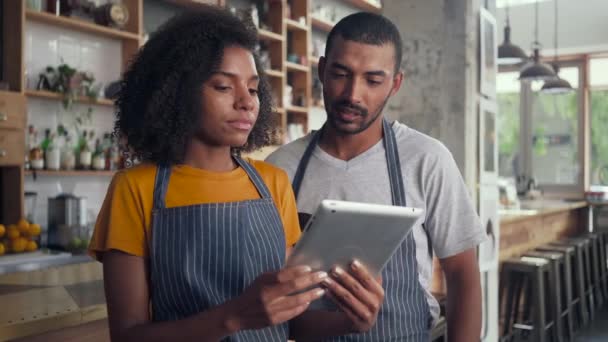 Dueño de café sonriente en delantal mirando tableta digital — Vídeo de stock