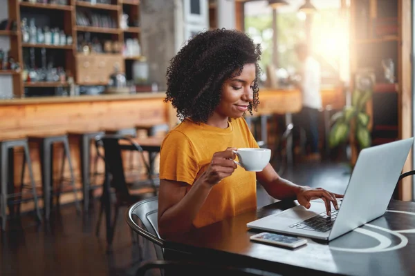 Jovem mulher segurando copo na mão usando laptop — Fotografia de Stock