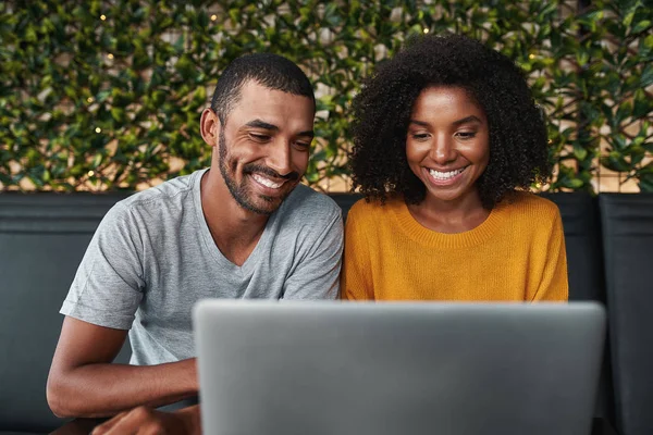 Sonriente pareja joven utilizando el ordenador portátil en un café moderno — Foto de Stock