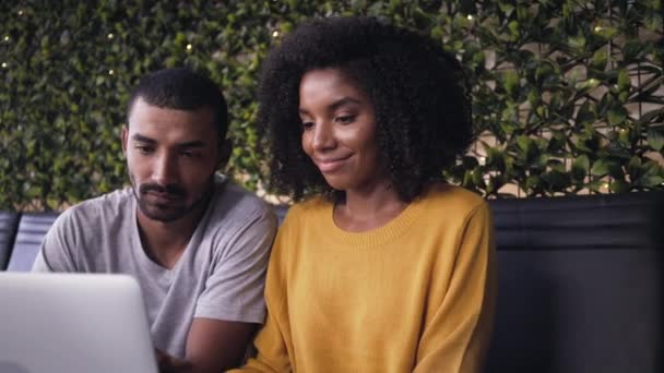 Молода пара дивиться на ноутбук у кафе — стокове відео