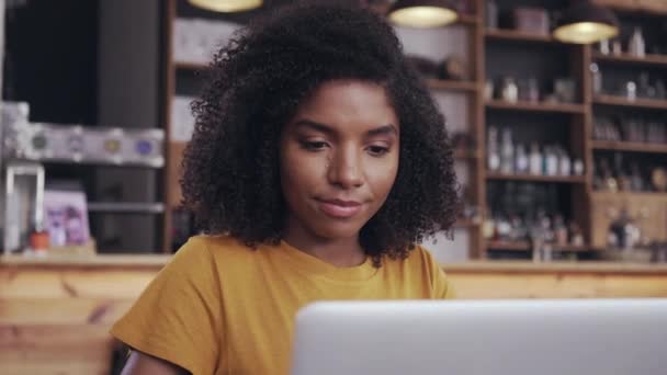 Νεαρή γυναίκα που χρησιμοποιεί φορητό υπολογιστή στο καφέ — Αρχείο Βίντεο