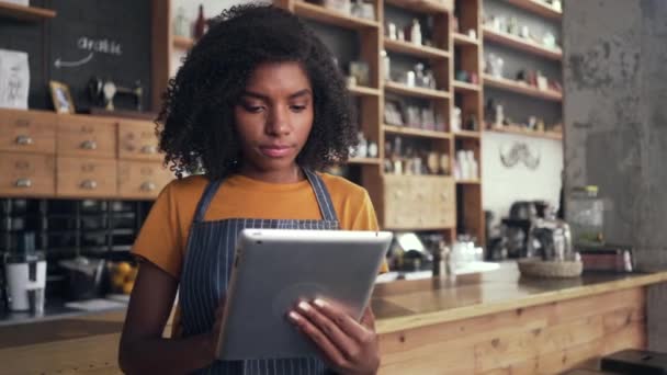 Dijital tablet kullanan Afrikalı bir kadın kafe sahibi — Stok video