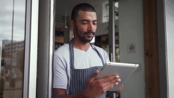 デジタルタブレットを使ってカフェの入り口に立つ男性オーナー — ストック動画