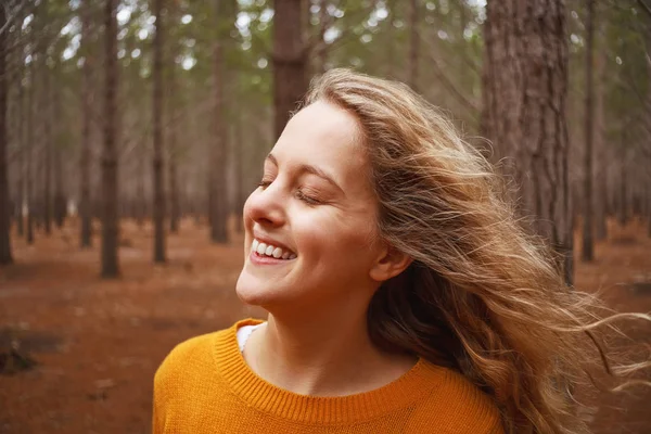Усміхнена молода жінка насолоджується свіжим повітрям у лісі — стокове фото
