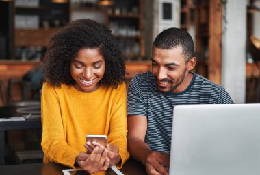 Gülümseyen çift kafede cep telefonu bakıyor