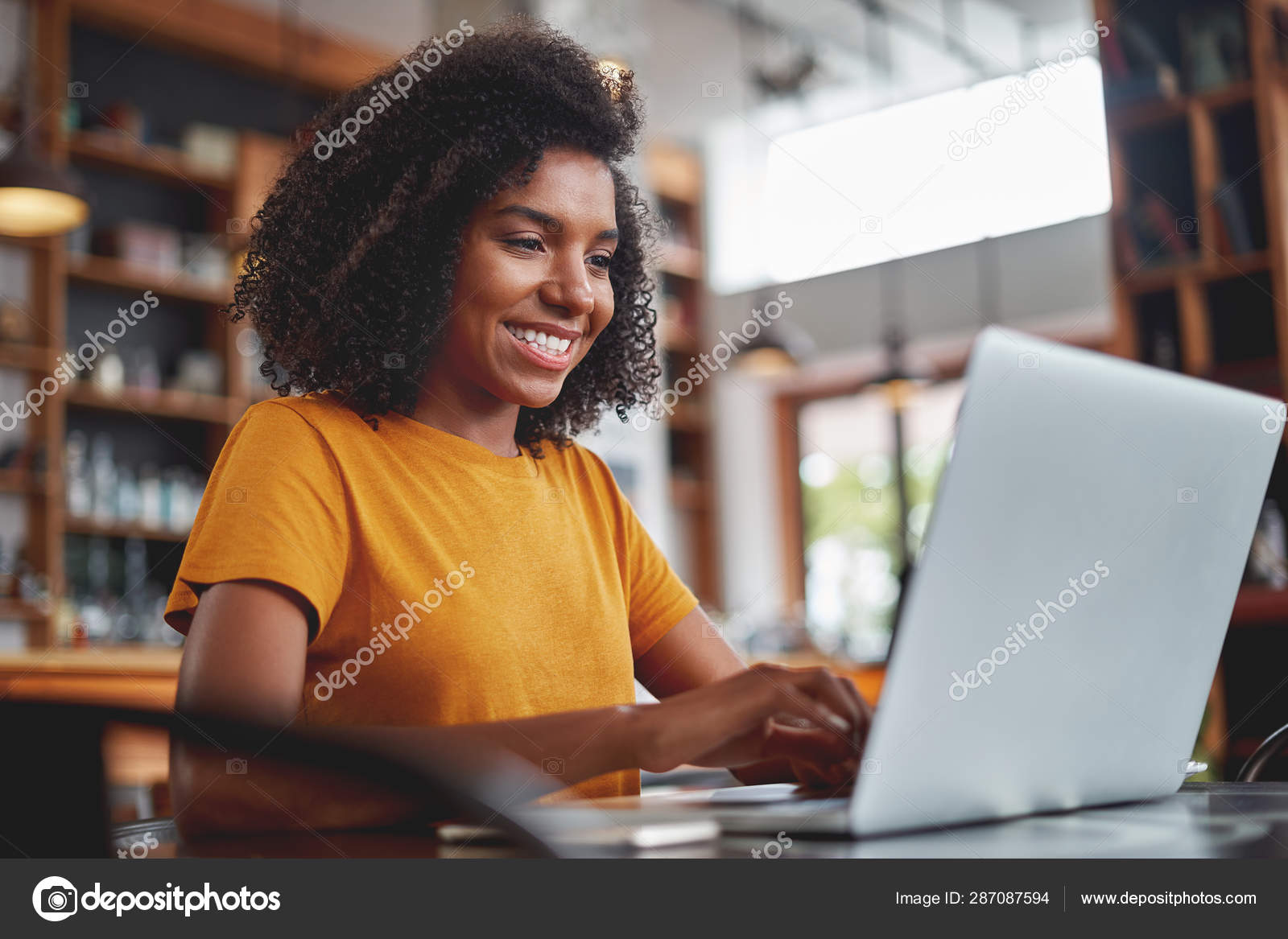 Happy young black woman using laptop in cafe Stock Photo by ©Stratfo