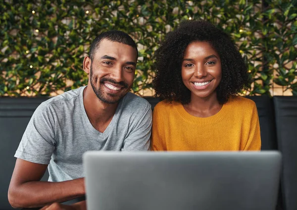 Sonriente pareja joven utilizando el ordenador portátil mirando a la cámara — Foto de Stock