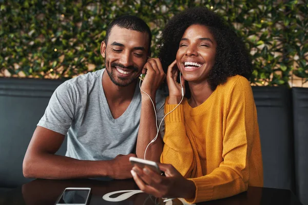 Genç çift mobil telefon müzik dinlemek için kulaklık paylaşımı