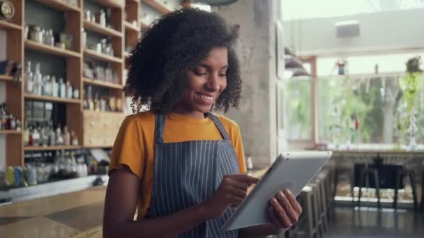 Молодая владелица использует цифровой планшет, стоя в кафе — стоковое видео