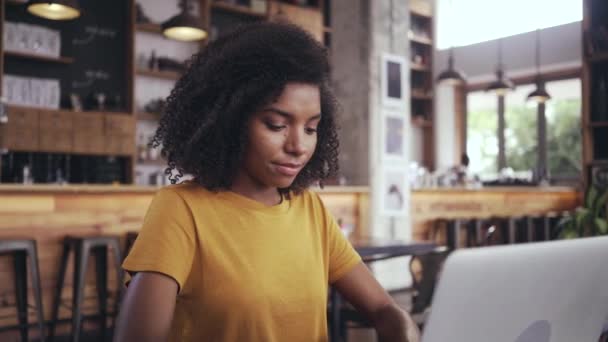 Mujer joven en la cafetería con el ordenador portátil — Vídeo de stock
