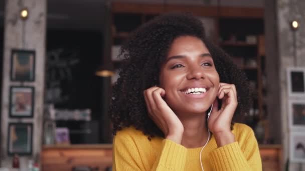 Mujer escuchando su auricular en un café — Vídeo de stock