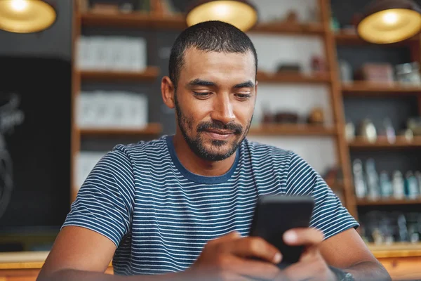 Giovane uomo razza mista utilizzando smartphone in caffè — Foto Stock