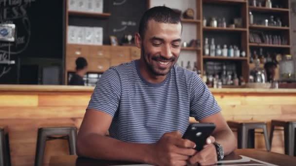 Portret uśmiechniętego człowieka za pomocą smartfona w kawiarni — Wideo stockowe