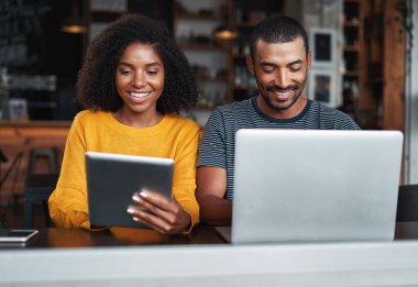 Kafede elektronik cihazları kullanmakla meşgul olan çift