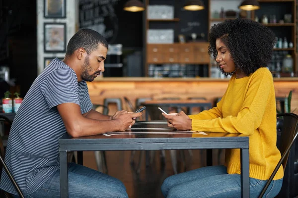 Pareja en la mesa de la cafetería usando teléfonos móviles no hablando — Foto de Stock