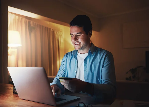 Lachende man genieten van online winkelen laat in de nacht met creditcard — Stockfoto