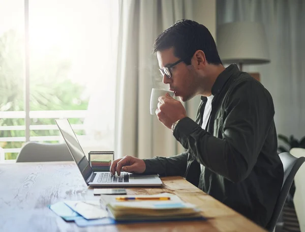 Man het drinken van koffie terwijl het werken op laptop thuis — Stockfoto