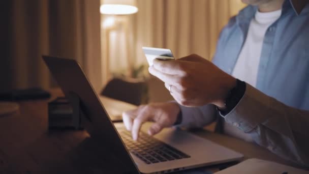 Een man online winkelen op laptop met creditcard bij late night — Stockvideo