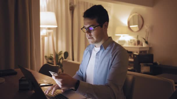 A man shopping online late at night using laptop and credit card — Stock Video