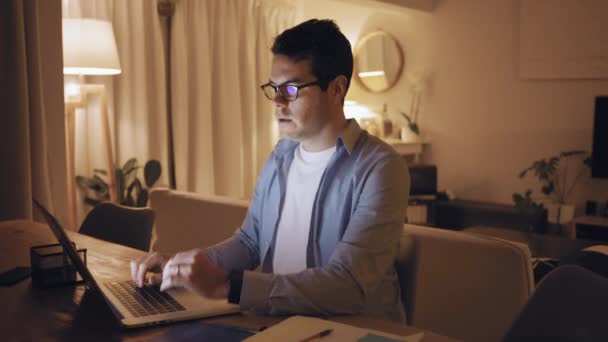 Unavený muž trpící bolestí krku, který pracuje až do pozdní noci na přenosném počítači — Stock video