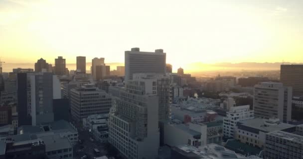 Clip de dron de la salida del sol brillando sobre una ciudad ocupada en el ajetreo temprano en la mañana — Vídeos de Stock