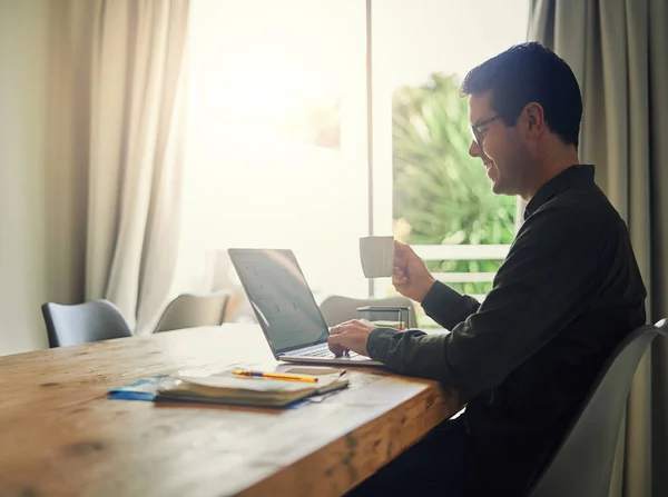 Man houdt kopje koffie in de hand met behulp van laptop op tafel — Stockfoto