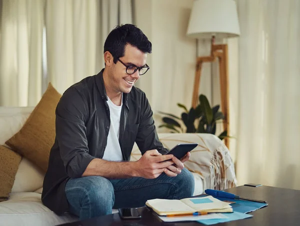 Sorrindo homem sentado no sofá usando tablet digital em casa — Fotografia de Stock