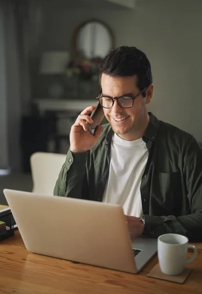 Gelukkige man praten op mobiele telefoon tijdens het gebruik van laptop thuis — Stockfoto